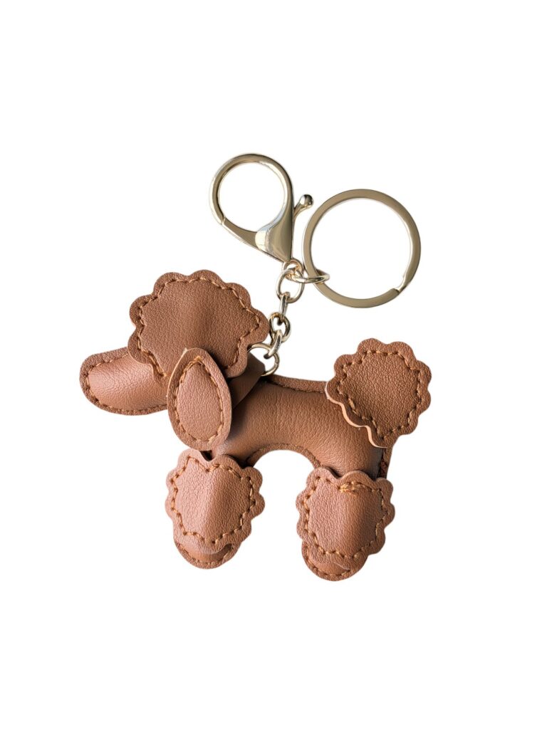 Brown poodle-shaped charm with stitched edges, a gold-tone clasp and keyring