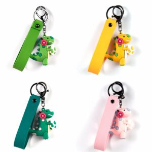 Four dinosaur figures wearing headphone accents with printed loop straps, rings and clips in green, yellow, teal, pink, red, black, silver-tone, shown as a keychain.