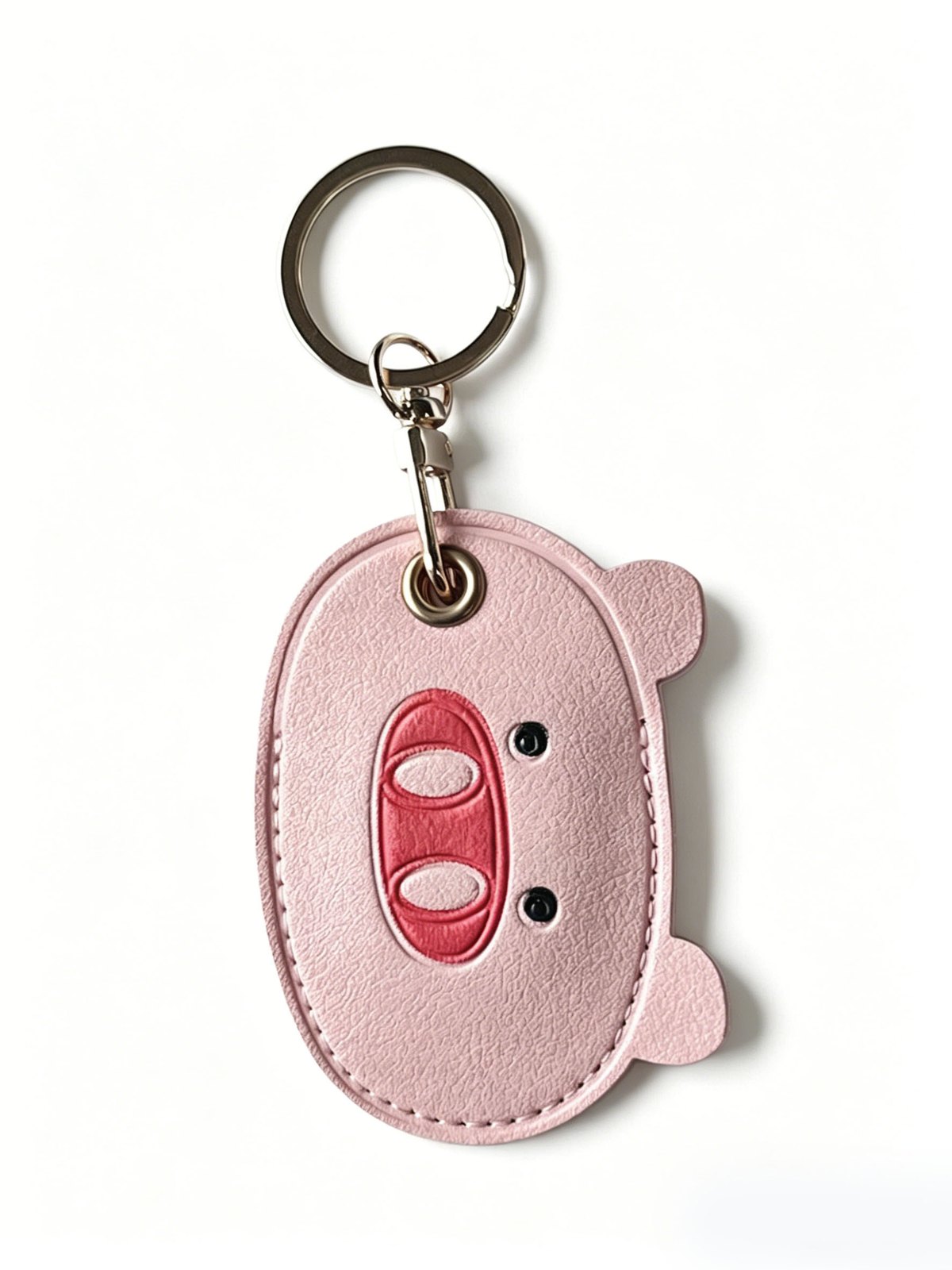 Pig face charm with round ring in pink, black, red, gold-tone, shown as a keychain.