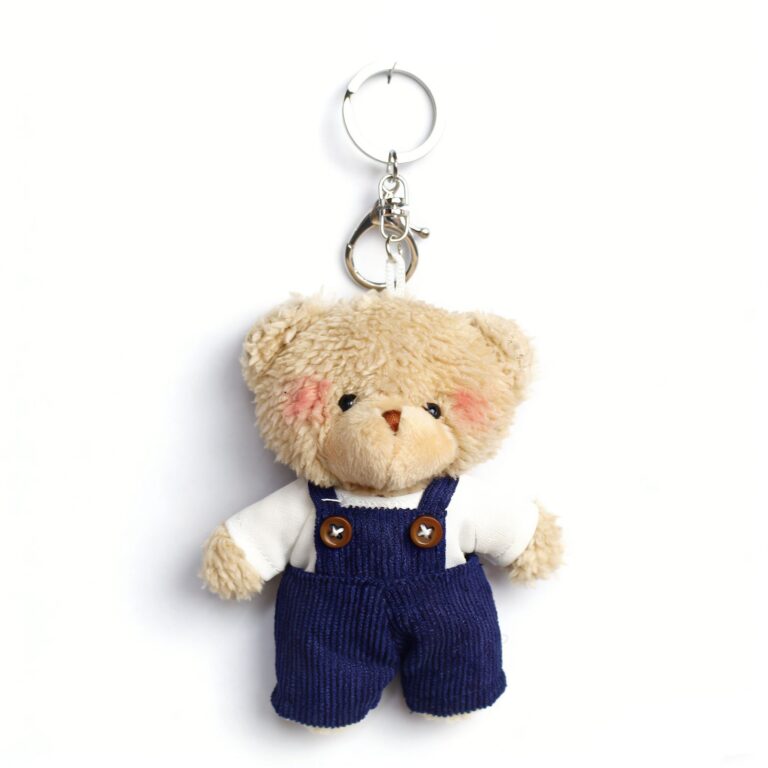 Tan plush bear keychain wearing blue overalls over a white shirt