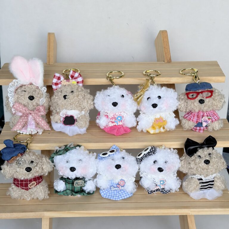 Small plush character bag charms in assorted outfits arranged on a wooden display stand
