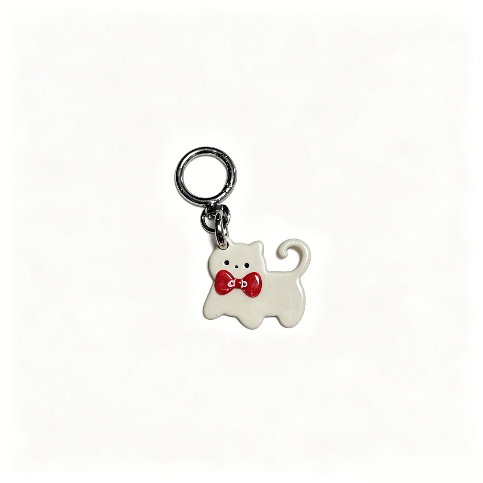 White cat-shaped bag charm with a red bow and curled tail