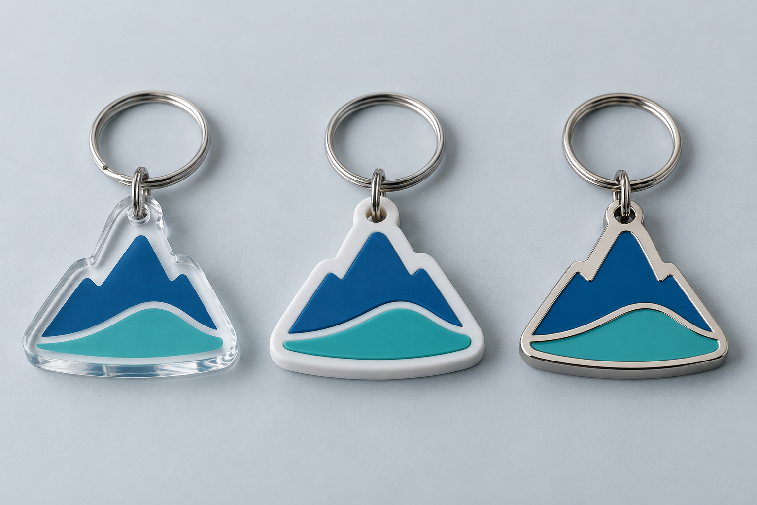 AI illustration comparing a similar mountain outline in clear acrylic, layered soft PVC and metal enamel.