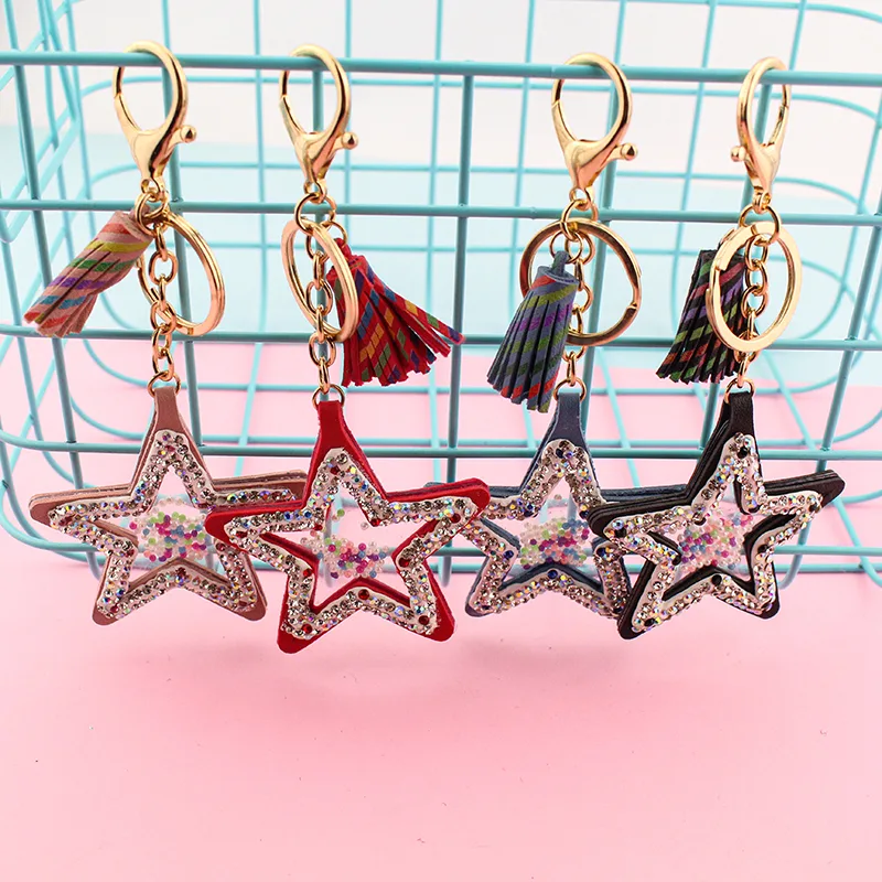 Four star-shaped charms in different colours, each with a tassel, ring and clasp, hanging on a wire basket.