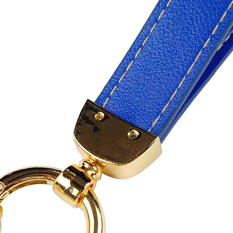 Close-up of a blue stitched strap, two round fasteners, a gold-tone end cap and a connecting ring.