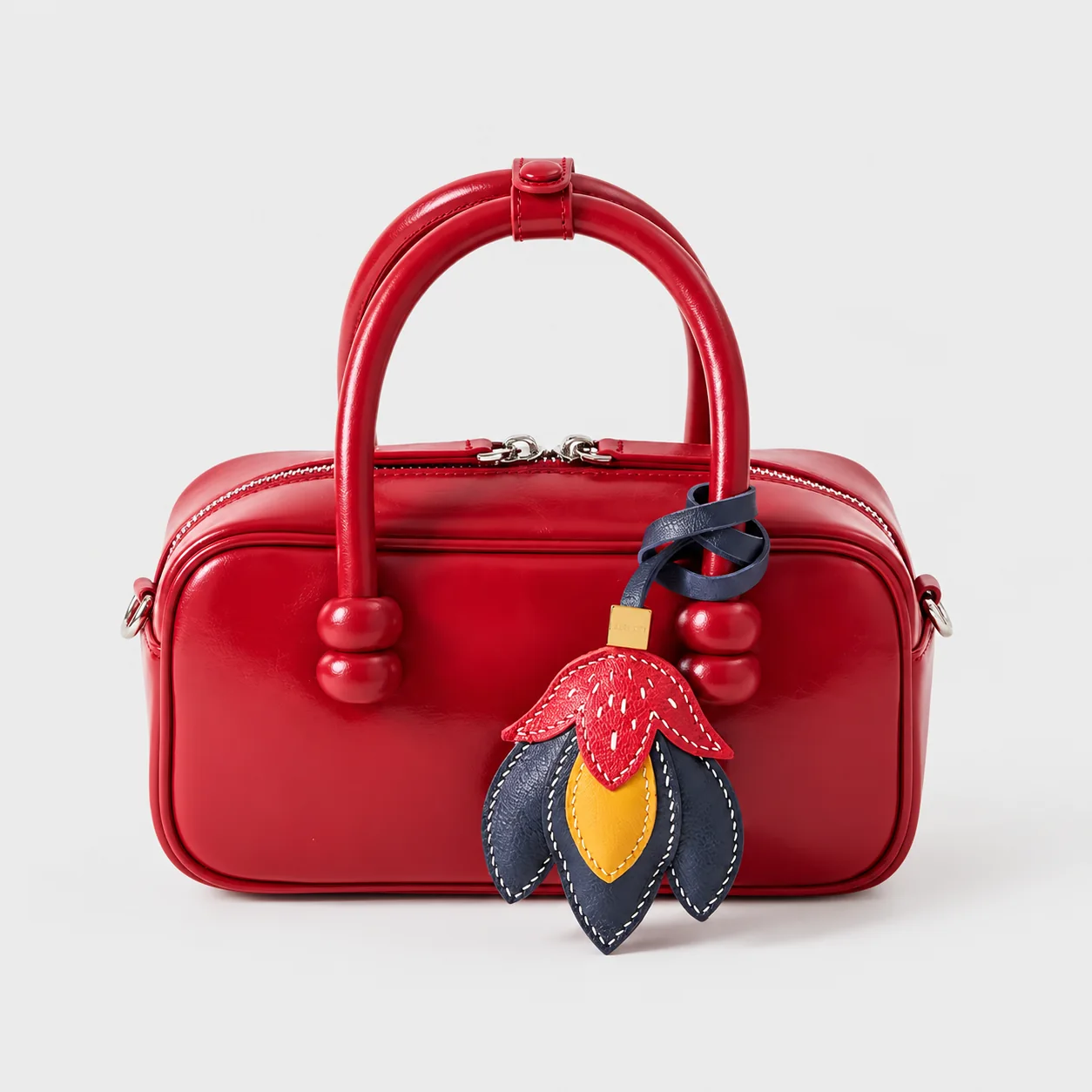 Custom leather and PU bag charm attached to a red handbag