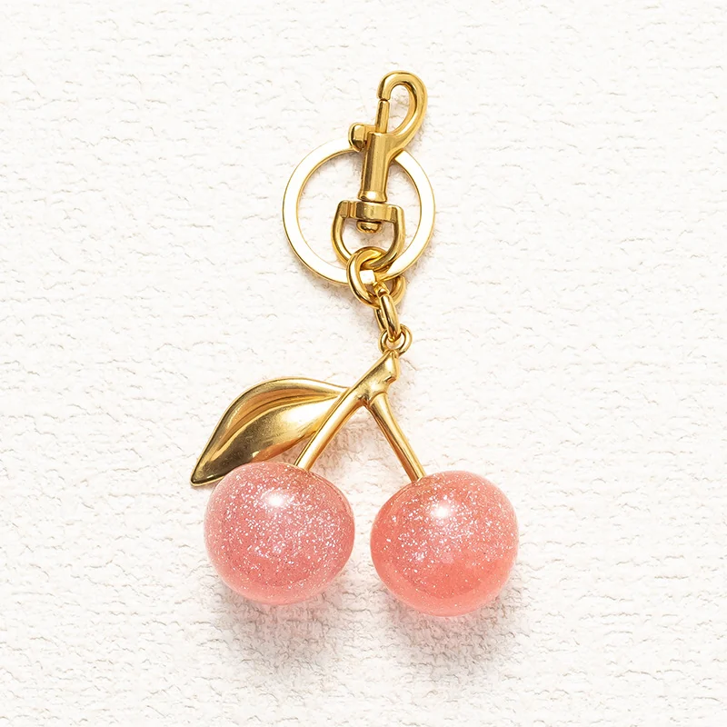 Pink cherry-shaped charm with a gold-tone leaf, short chain, ring and clasp