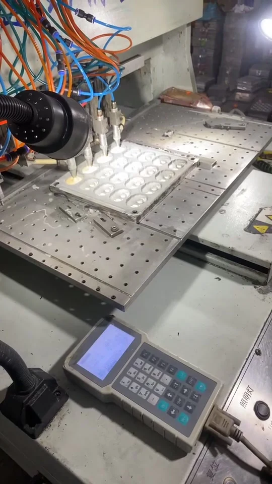 Video frame showing feed needles dispensing material into a multi-cavity metal mold