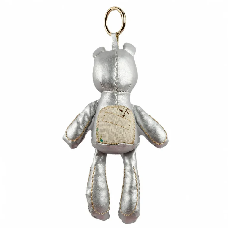 Glossy bear-shaped padded figure with stitched limbs, chain and clip in silver-tone, beige, red, gold-tone, shown as a keychain.