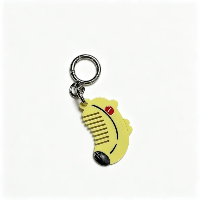 Banana-shaped comb charm with heart and round ring in yellow, black, red, silver-tone, shown as a keychain.
