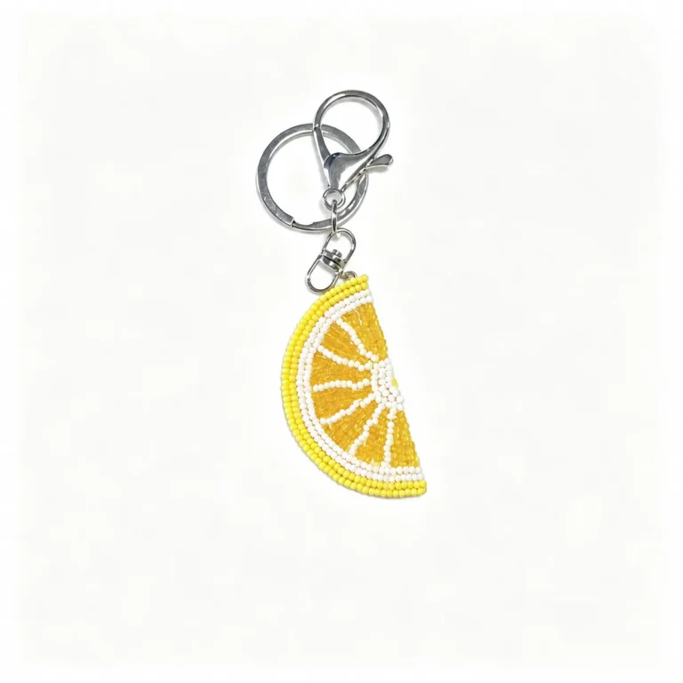 Beaded citrus wedge charm with clasp and round ring in yellow, white, silver-tone, shown as a keychain.