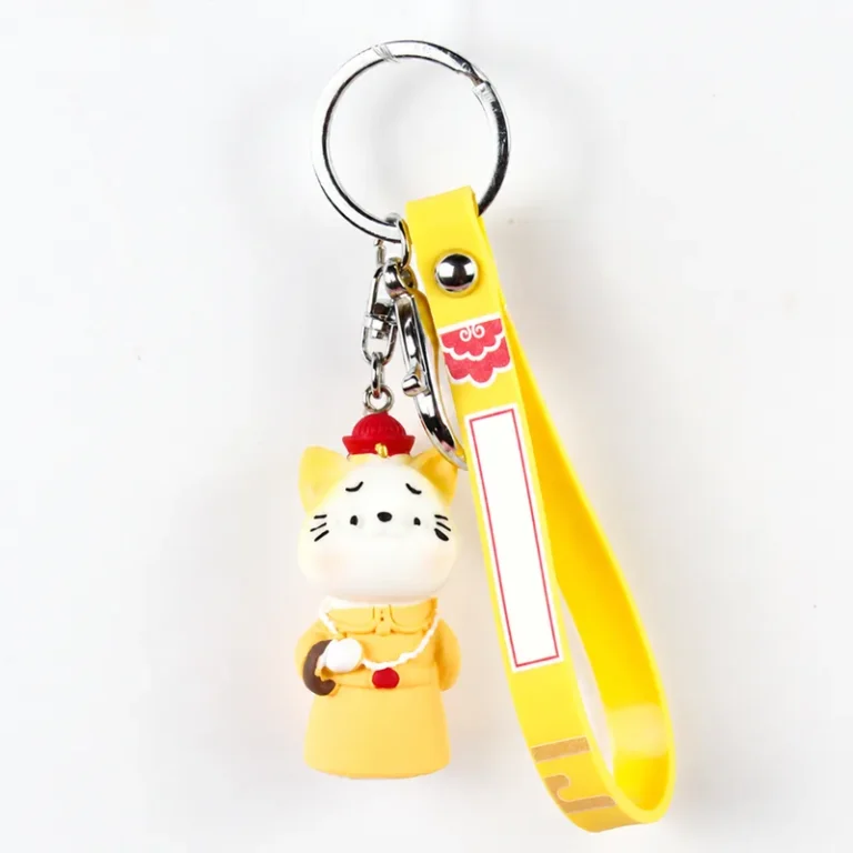 Cat figure wearing robe with printed loop strap and key ring in white, yellow, red, silver-tone, shown as a keychain.